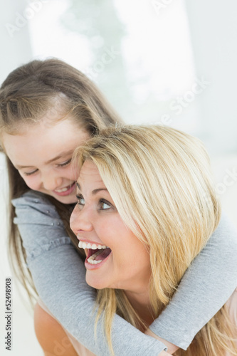 Laughing mother giving daughter a piggy back