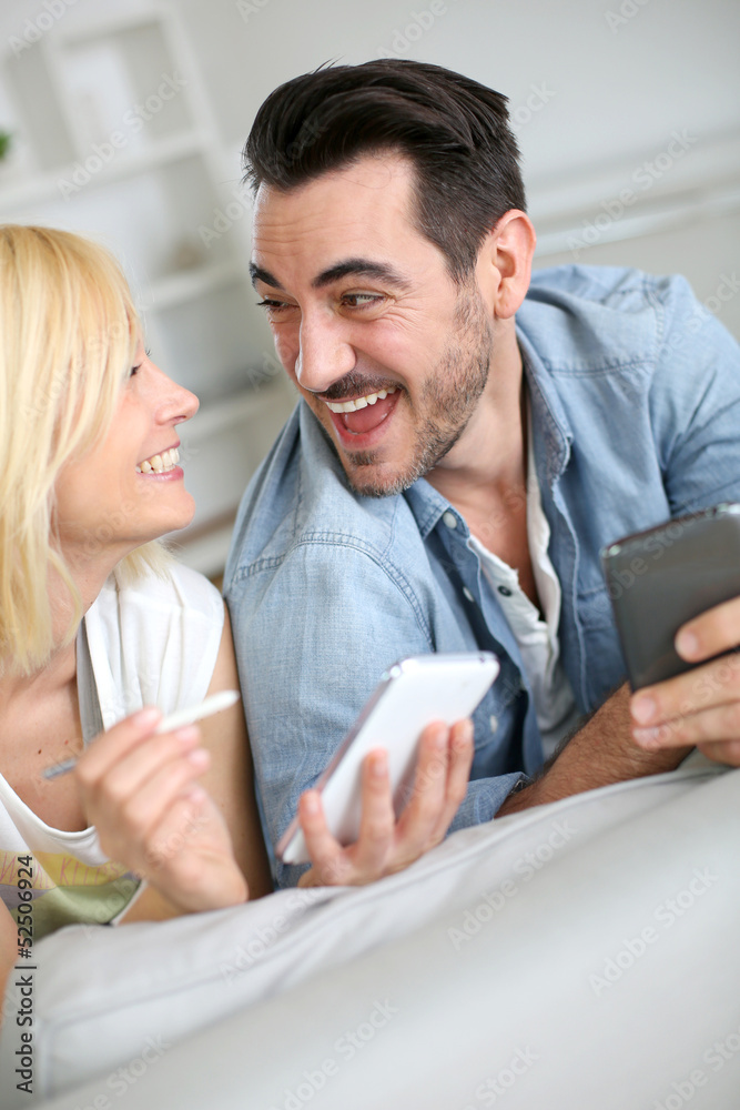 Cheerful couple having fun using smartphone Cheerful couple having fun using smartphone
