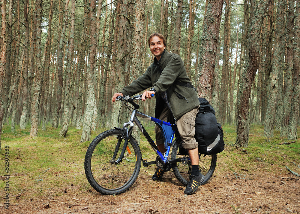 Young man on bicycle with backpack in forest - bicycle travel Young man on bicycle with backpack in forest - bicycle travel