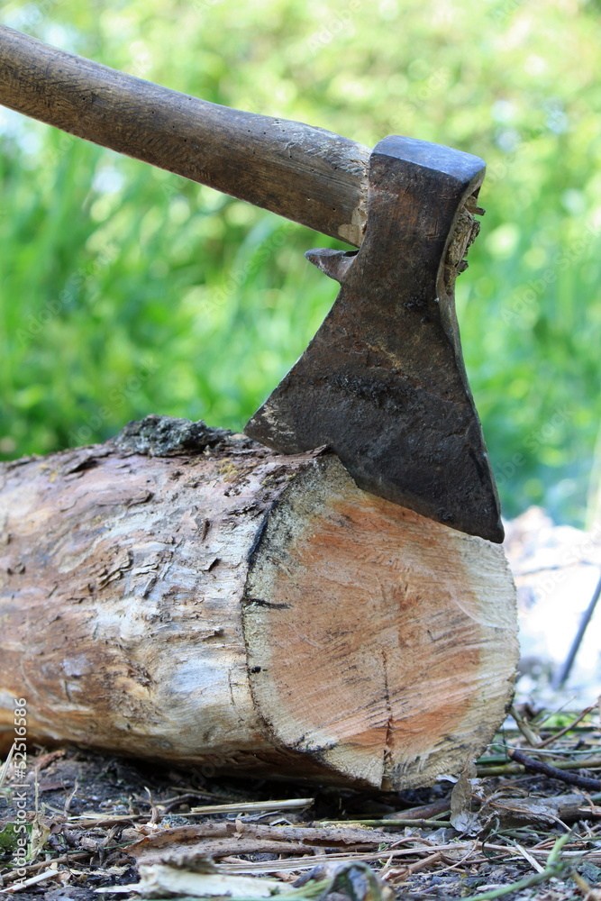 Ax in a log on the background of green grass Ax in a log on the background of green grass
