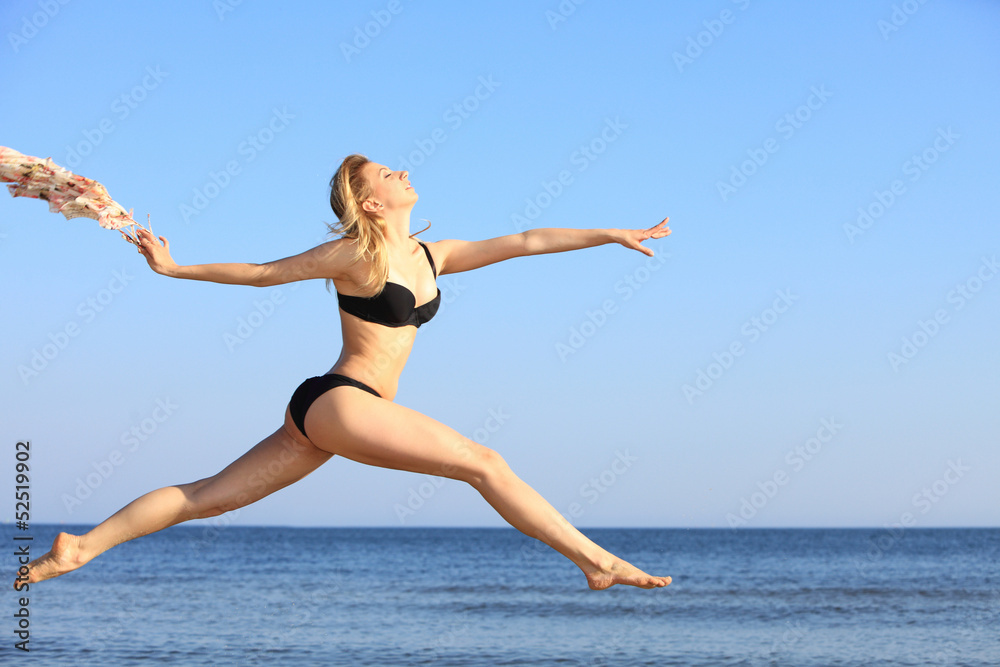 Young woman jumping on beach fit sporty girl