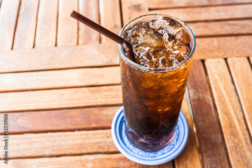 Fresh black soda with ice on wood table