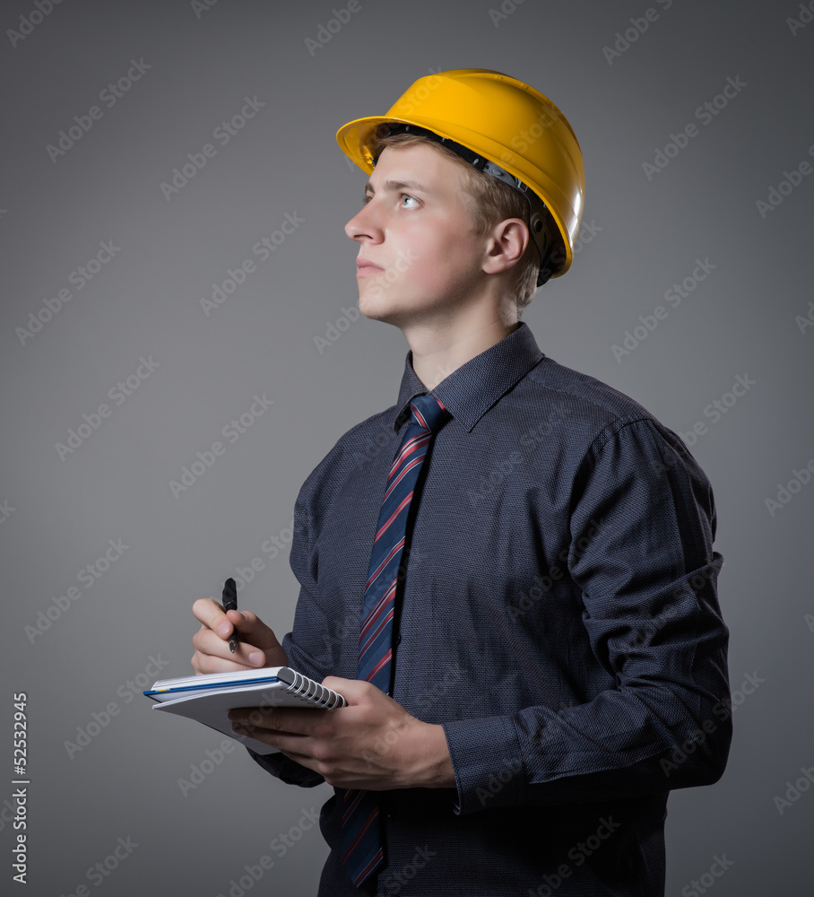 young builder in a building helmet with a notebook in hands young builder in a building helmet with a notebook in hands