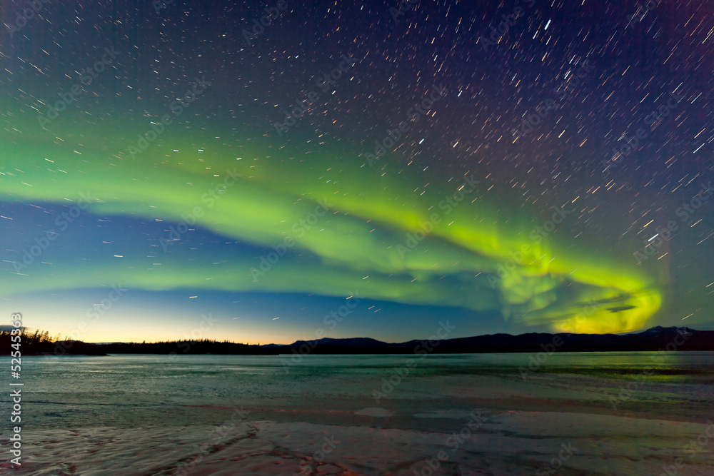 Northern Lights and morning dawn over frozen lake