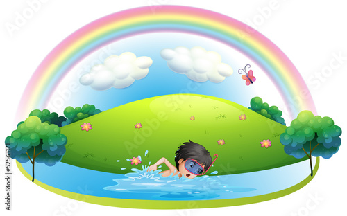 A boy swimming at the beach near the hill