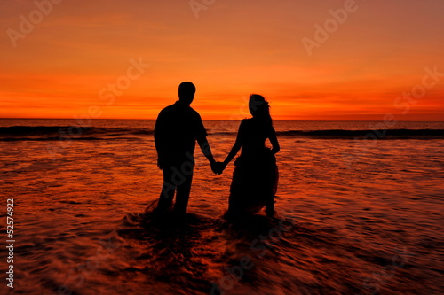Silhouette / Shape of a bride and groom on the beach at sunset