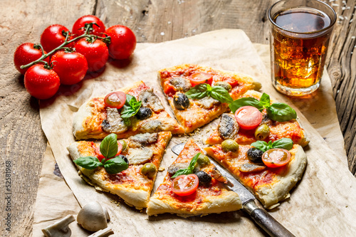 Baked pizza with fresh ingredients on old wooden table