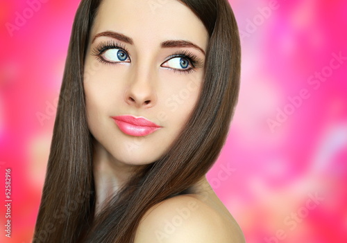 Beautiful woman face on pink background. Closeup portrait