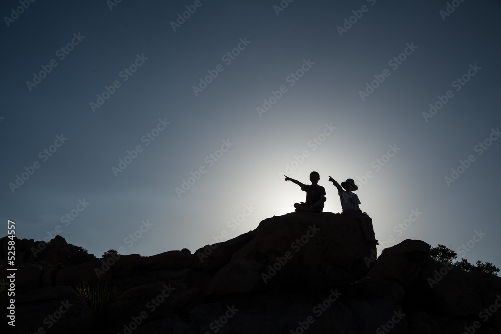 Two children pointing, sitting on rock