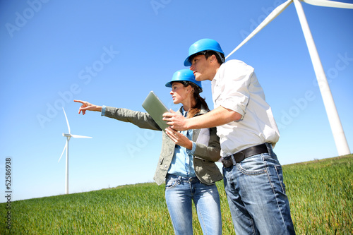 Engineers looking at wind turbine site with tablet