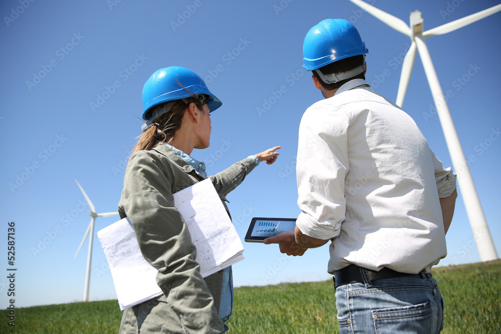 Engineers looking at wind turbine site with tablet Engineers looking at wind turbine site with tablet