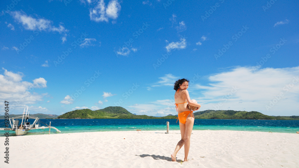 beautiful bikini girl holding coconut looks back on white beach beautiful bikini girl holding coconut looks back on white beach