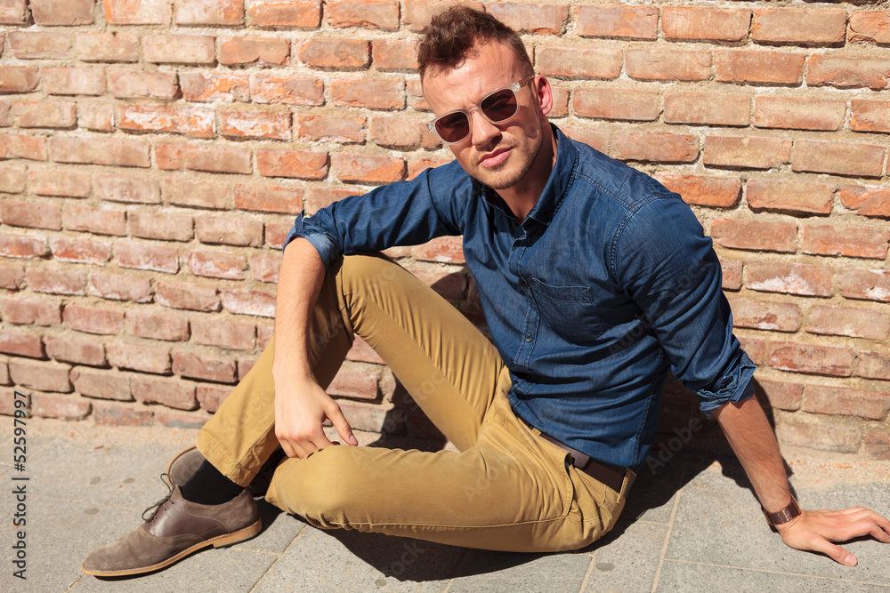 casual man seated by brick wall casual man seated by brick wall