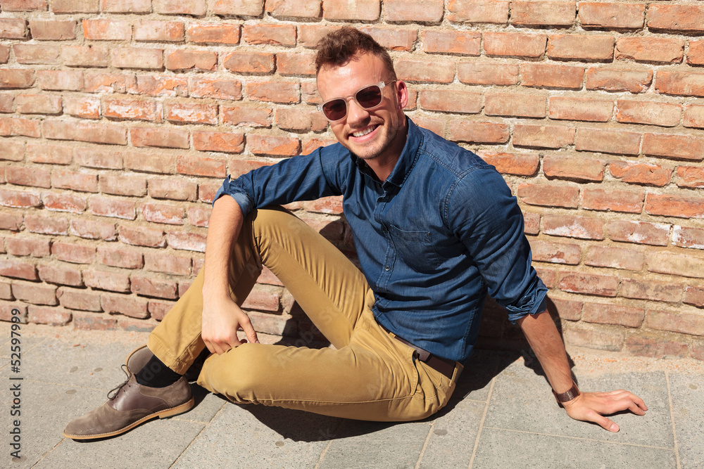 casual man sits happy on sidewalk casual man sits happy on sidewalk