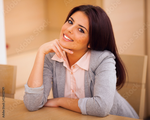 Young confident smiling woman sitting at the table