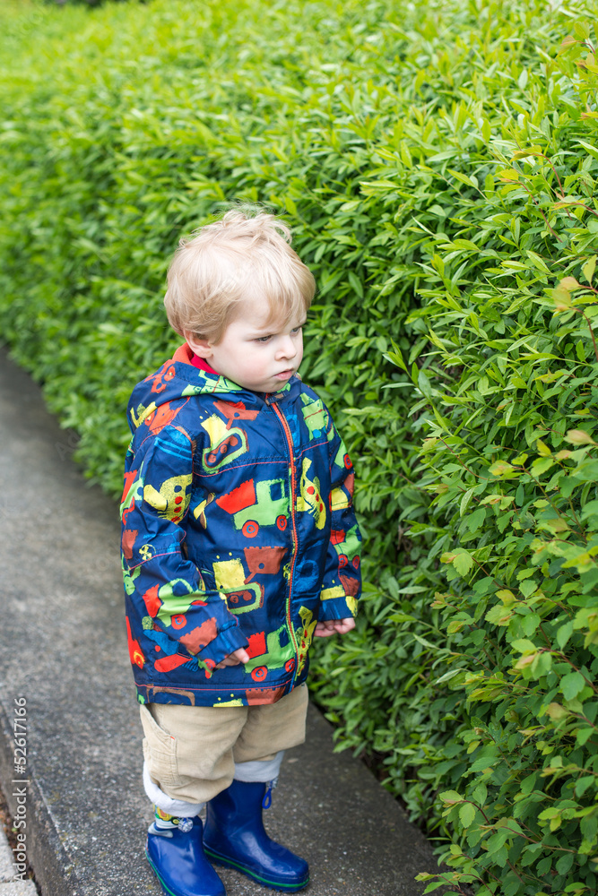 Little toddler boy in rain clothes, outdoors Little toddler boy in rain clothes, outdoors