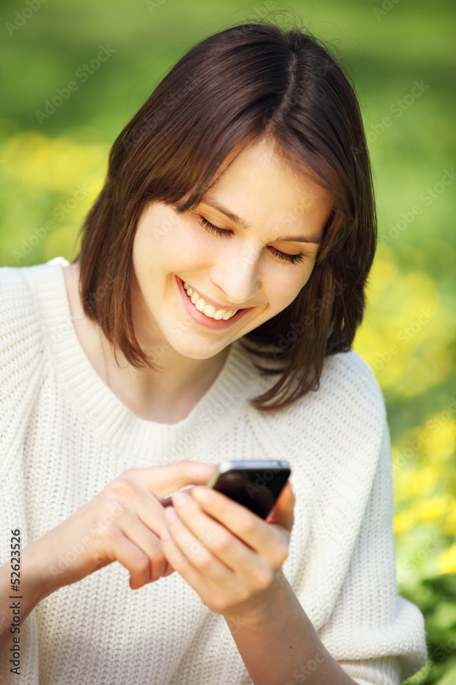 Image of young beautiful woman in summer park reading a message