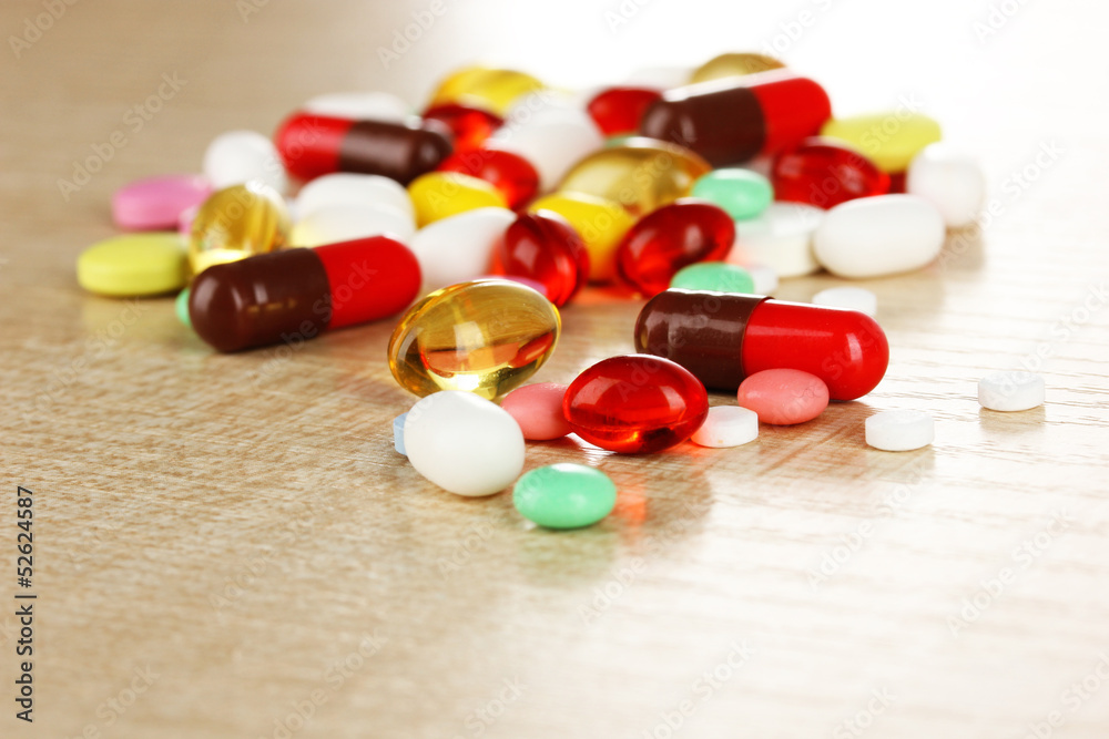 Assortment of pills, tablets and capsules on wooden table Assortment of pills, tablets and capsules on wooden table