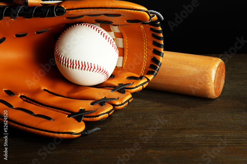Baseball glove, bat and ball on dark background