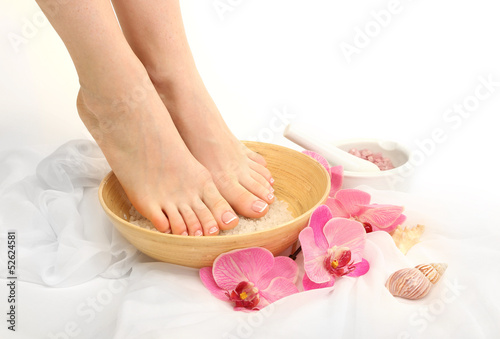 Female feet in spa bowl with sea salt, isolated on white