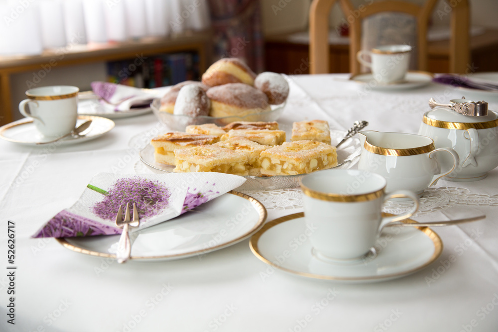 Table with coffe or tea cups, cake, plates and doughnuts Table with coffe or tea cups, cake, plates and doughnuts