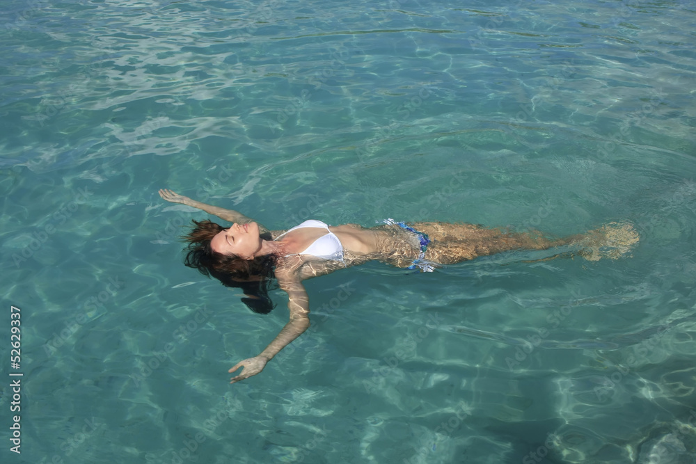 Young woman in bikini floating in clear water