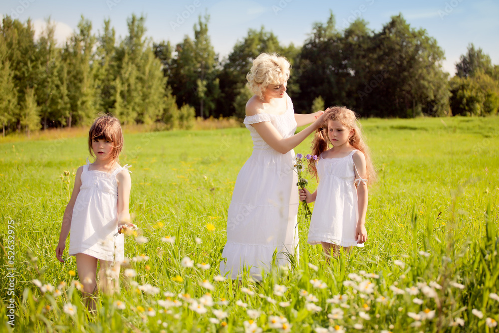 Mother and daughters relaxing on the meadow Mother and daughters relaxing on the meadow