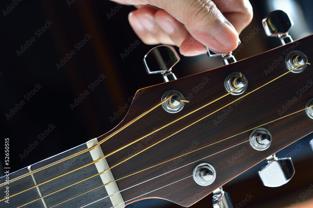 Obraz premium Hand tuning a guitar from headstock