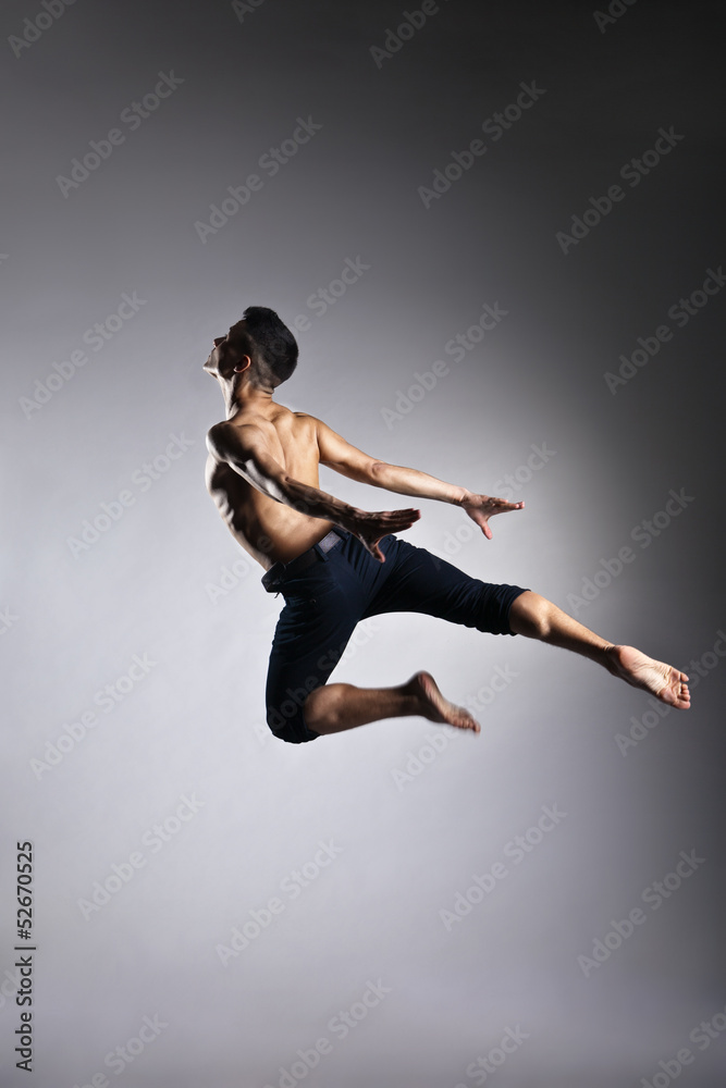 Caucasian man gymnastic leap posture on grey