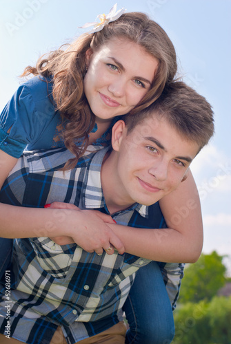 Happy teenage couple embracing over blue sky