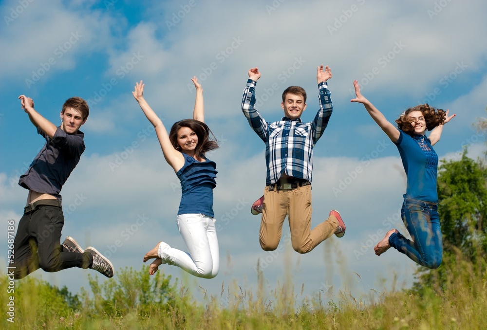 Four happy teenage friends boys and girls jumping high Four happy teenage friends boys and girls jumping high