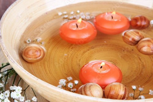 Beautiful candles in water on wooden table close-up