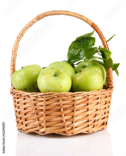 Juicy green apples with leaves in basket, isolated on white