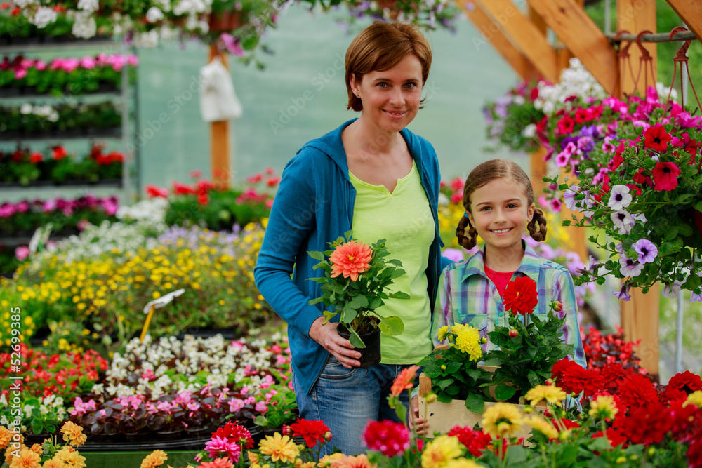 Mother with daughter shopping plants and flowers in garden cente