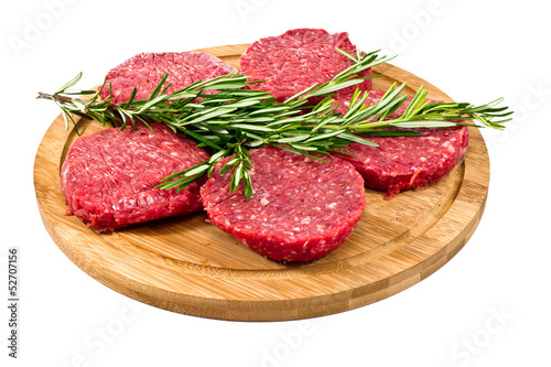 raw hamburgers with cellophane and rosemary on wooden board