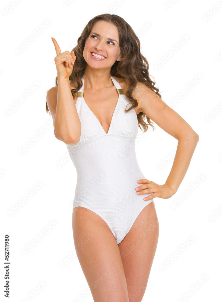Smiling young woman in swimsuit pointing up on copy space Smiling young woman in swimsuit pointing up on copy space