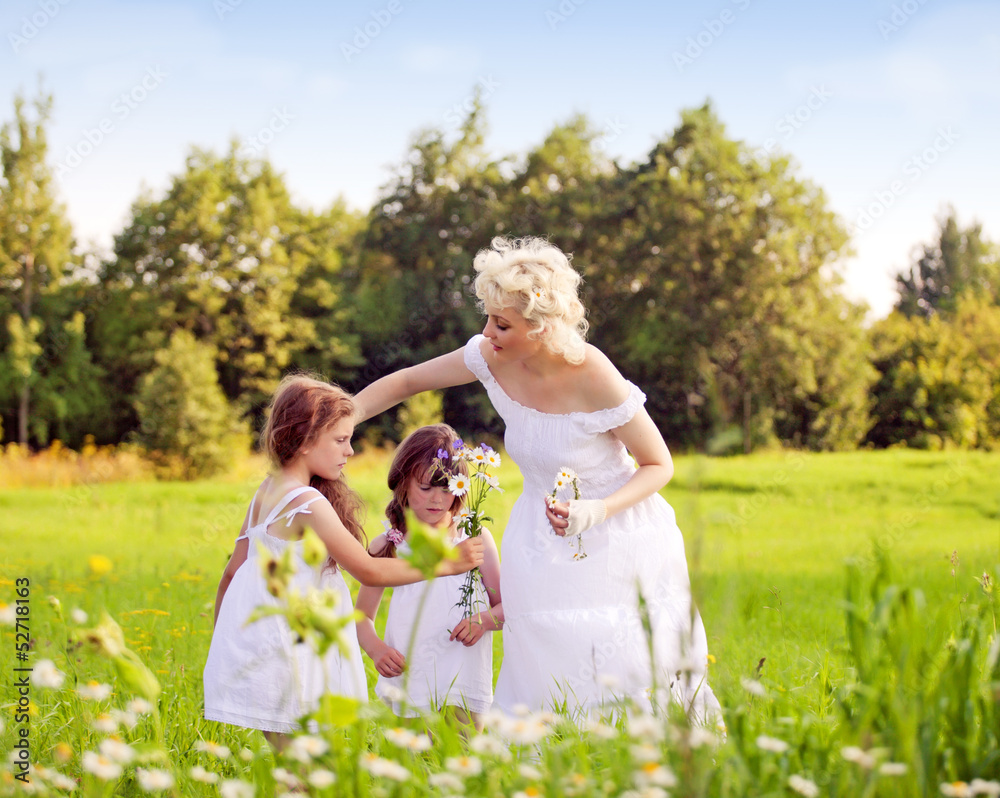 Mother and daughters relaxing on the meadow Mother and daughters relaxing on the meadow
