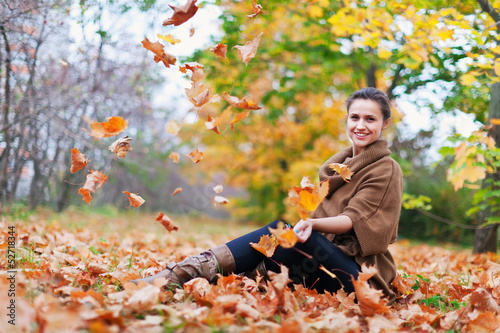 woman throws autumn leaves