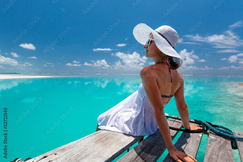 Caucasian woman takes rest at wooden pier to Indian ocean