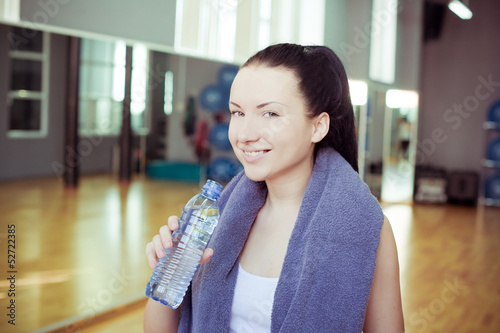 Young woman at the gym drinks water 
