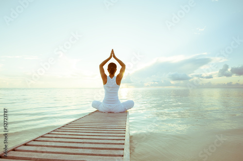 Fotografering Caucasian woman practicing yoga at seashore