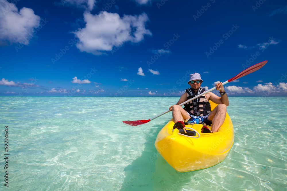 Young caucasian man kayaking in sea at Maldives