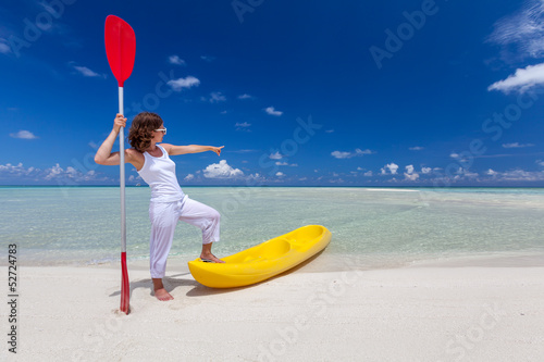 Young caucasian woman keeps paddle at the seashore near yellow k