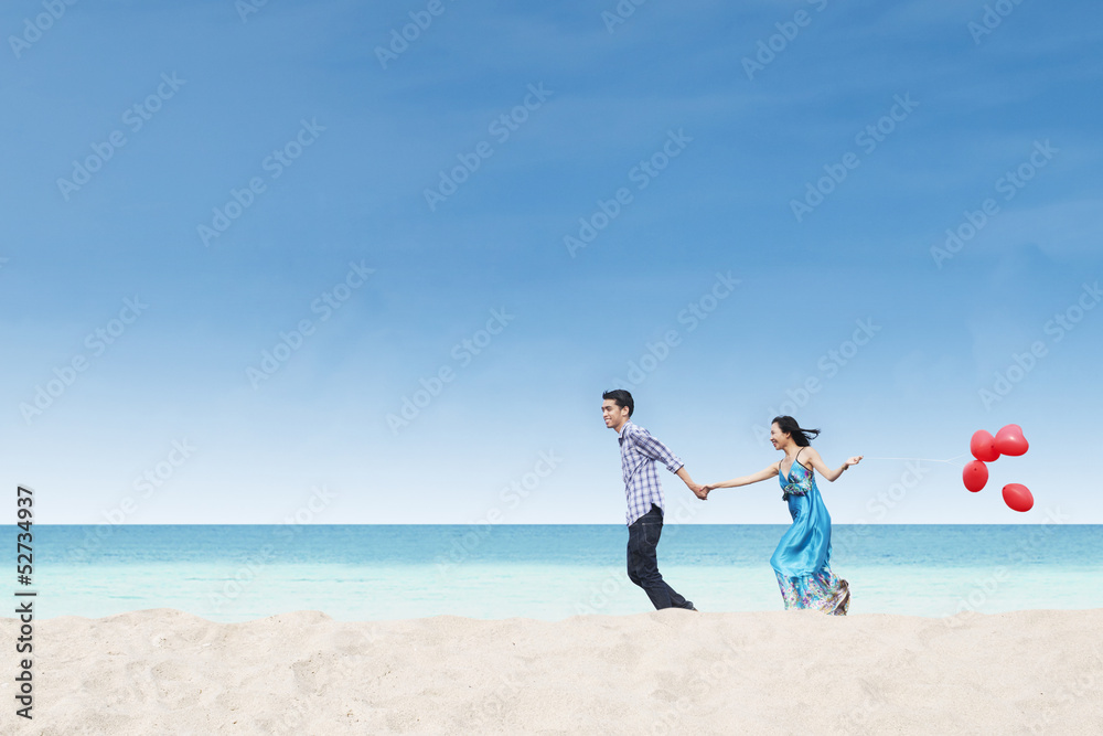 Running couple at beach wih balloons