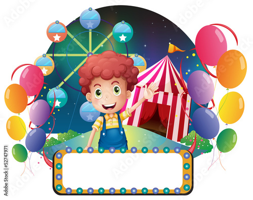 A boy with an empty signage in front of a carnival