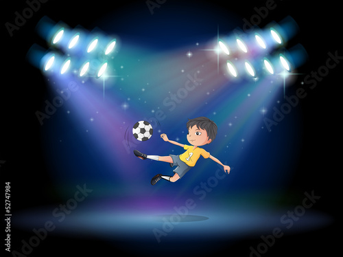 A boy kicking the soccer ball at the stage