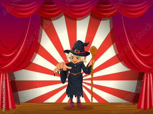 A scary witch holding a stick at the stage