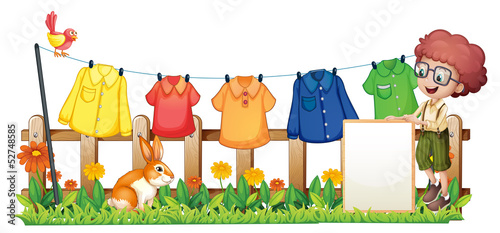 A boy holding an empty frame in front of the hanging clothes