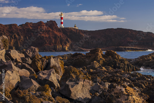 Cliff rocky coast and lighthouse at sunset