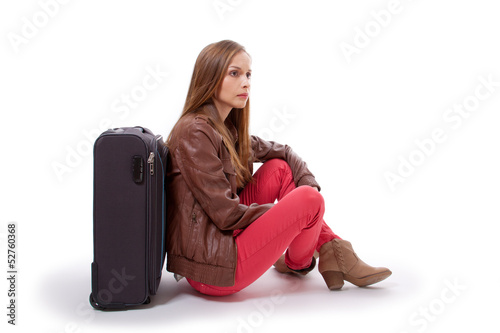 Girl sitting near a suitcase, isolated on white background